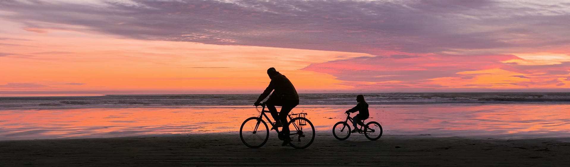 Dad and daughter biking at sunset